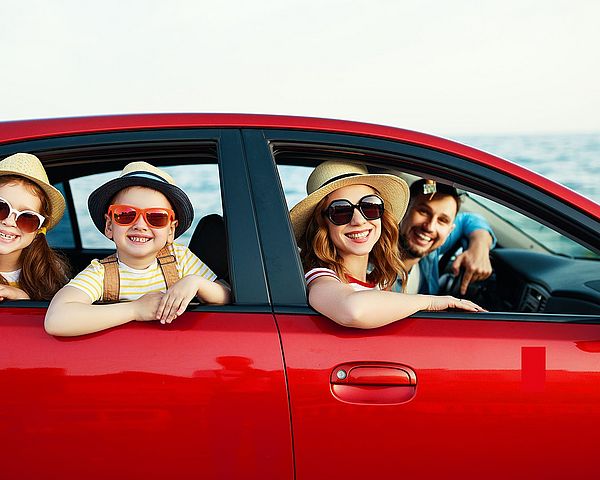 Eine glückliche Familie - Vater, Mutter und Kinder fahren mit dem Auto in den Urlaub.
